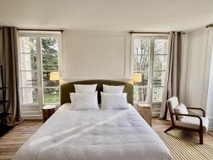 a bedroom with a large bed and two windows at Château Royal de Benays - Hôtel in Benais +54 photos