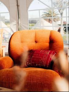 an orange chair with a red pillow on it at Glamping Spot - Penmarch in Penmarch