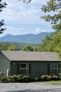a green house with mountains in the background at The Firefly Lodge at Shenandoah in Rileyville