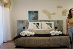 a woman standing next to a bed with rolled towels at Flá Suite Castello in Cagliari