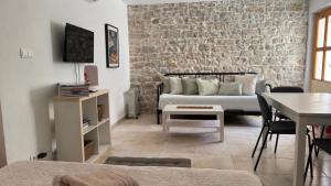 a living room with a couch and a brick wall at Stone house Olsavinia close to the beach in Kaštela