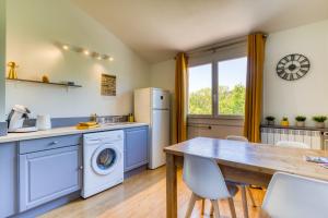 a kitchen with a washing machine and a table at Les Pénates De Mélilotte in Clermont-lʼHérault
