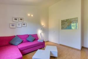 a living room with a pink couch and a table at Les Pénates De Mélilotte in Clermont-lʼHérault