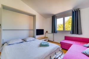 a bedroom with two beds and a pink couch at Les Pénates De Mélilotte in Clermont-lʼHérault