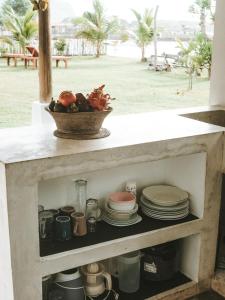 a cabinet filled with dishes and a bowl of fruit at Muara Surf House - Yoyos beachfront in Sekongkang +26 photos