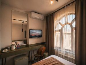 a bedroom with a bed and a desk and a window at The Destan Hotel and Terrace in Baku