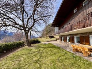 a wooden bench next to a building with a tree at Villa ai noci in Carano
