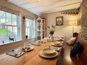 a dining room with a wooden table with plates and glasses at Wingrove Cottage - Sleeps 8 in Morland