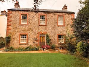 an old stone house with a lawn in front of it at Wingrove Cottage - Sleeps 8 in Morland