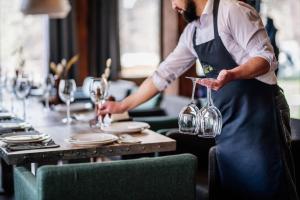 a man in an apron pouring wine into glasses at Teghenis Resort in Tsaghkadzor
