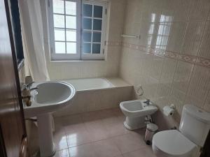 a bathroom with a sink and a toilet and a tub at Casa Pascoal in Ribeira Grande