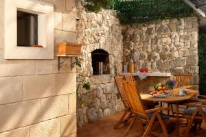 a table and chairs in a patio with a stone wall at Heritage House Pjaca, Omiš in Omiš