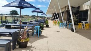 a row of tables and chairs with umbrellas outside a building at Moonah Links - Apartment 43 in Fingal