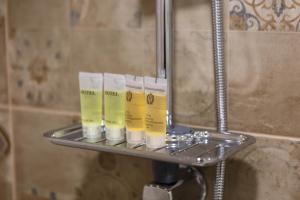 a shelf in a bathroom with four toiletries on it at Golden Pheasant in Tbilisi City +149 photos
