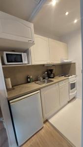 a small kitchen with white cabinets and a microwave at Modern studio apartment near the harbor and city center in Lappeenranta