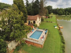 an overhead view of a house with a swimming pool next to a river at Gîtes BEAUSOLEIL in Campsegret