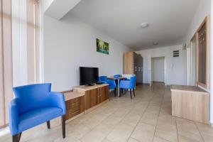 a living room with a blue chair and a television at Vila Pepic in Dobra Voda