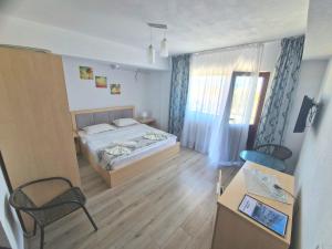 a bedroom with a bed and a chair and a table at Villa Sunset Beach Mamaia Nord in Mamaia Sat/Năvodari