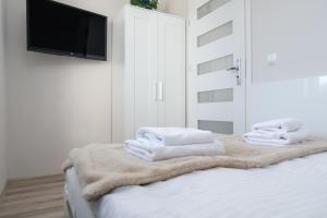 a white bedroom with a bed with towels on it at Apartamenty Izerskie - ul. Cicha 13D-E in Świeradów-Zdrój +49 photos