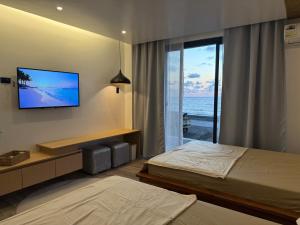 a hotel room with two beds and a flat screen tv at The Beach House by SYNCO in Lubong