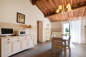 a kitchen and dining room with a table and a tv at Relais Le Fornacelle in Castagneto Carducci