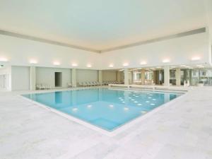 a large swimming pool with blue water in a building at Sport & Wellness Hotel San Gian in St. Moritz