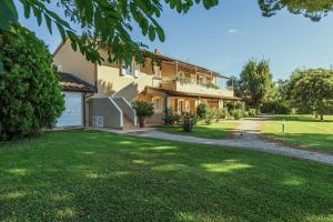 a house with a green lawn in front of it at Relais Le Fornacelle in Castagneto Carducci
