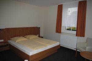 a bedroom with a bed and a window and a chair at Hotel Schützenhaus Jessen in Jessen