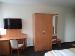 a bedroom with a desk and a cabinet with a television at Hotel Schützenhaus Jessen in Jessen