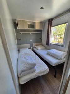 two beds in a small room with a window at camping la plage de l'orb in Cessenon