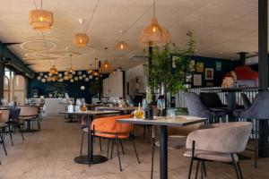 a restaurant with tables and chairs and pendant lights at Golden Tulip Hotel & Rooftop Martigues Provence in Martigues