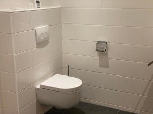a white bathroom with a toilet and a toilet paper dispenser at Den Doezel in Vorden +6 photos