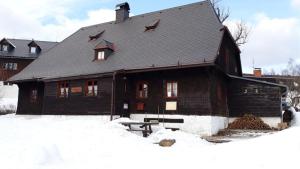 a large wooden house with a roof in the snow at U Jakuba - Boba in Prášily