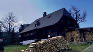 a large black house with a pile of logs at U Jakuba - Boba in Prášily
