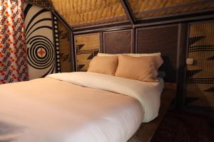 a bed with white sheets and pillows in a room at Noble Cheer in Ruhengeri