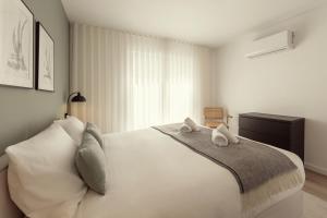 a bedroom with a white bed with towels on it at Casa Jacinto 9 in Caldas da Rainha
