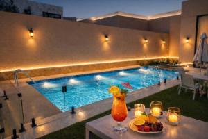 a table with a drink and fruit next to a swimming pool at منتجع ليورا ــ Liora Resort in Al Ḩanī