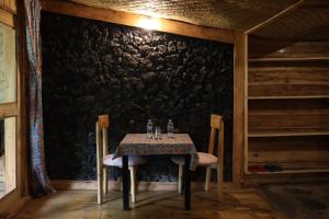 a table and chairs in a room with a stone wall at Noble Cheer in Ruhengeri
