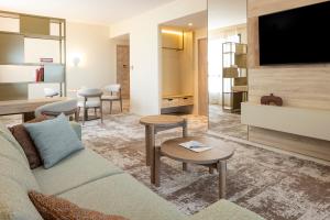 a living room with a couch and a flat screen tv at Parkest Hôtel & Spa in Genas