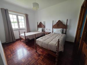 a bedroom with two beds and a window at Casa Pascoal in Ribeira Grande