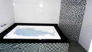 a black and white bathroom with a bath tub at Alpino Motel by Drops in Jundiaí