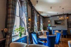 a restaurant with blue chairs and a table and a window at Crescent Inn by Maison Pierre in Ilkley