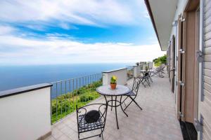 a balcony with tables and chairs and the ocean at Coastal Escape, Amalfi in San Lazzaro Agerola