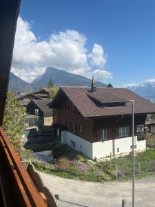 a red and white house with mountains in the background at Landliebi 3-room apartment in Faulensee