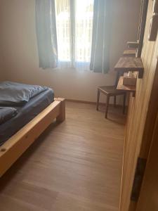 a bedroom with a bed and a desk and a window at Landliebi 3-room apartment in Faulensee