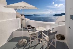 a balcony with a table and two chairs and an umbrella at ROCK CAVE HOUSE in Oia