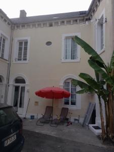 a red umbrella and chairs in front of a house at la bananeraie in Pouilly-sur-Loire