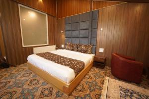 a bedroom with a large bed and a chair at hotel gulmarg hills in Gulmarg