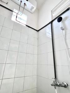 a shower in a bathroom with white tiles at Bromo Breeze Malang in Malang +46 photos