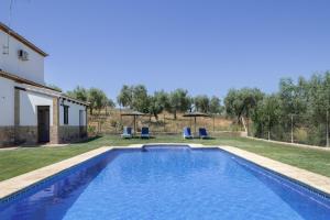 a swimming pool in a yard with chairs and umbrellas at La Pedrosa in La Cimada